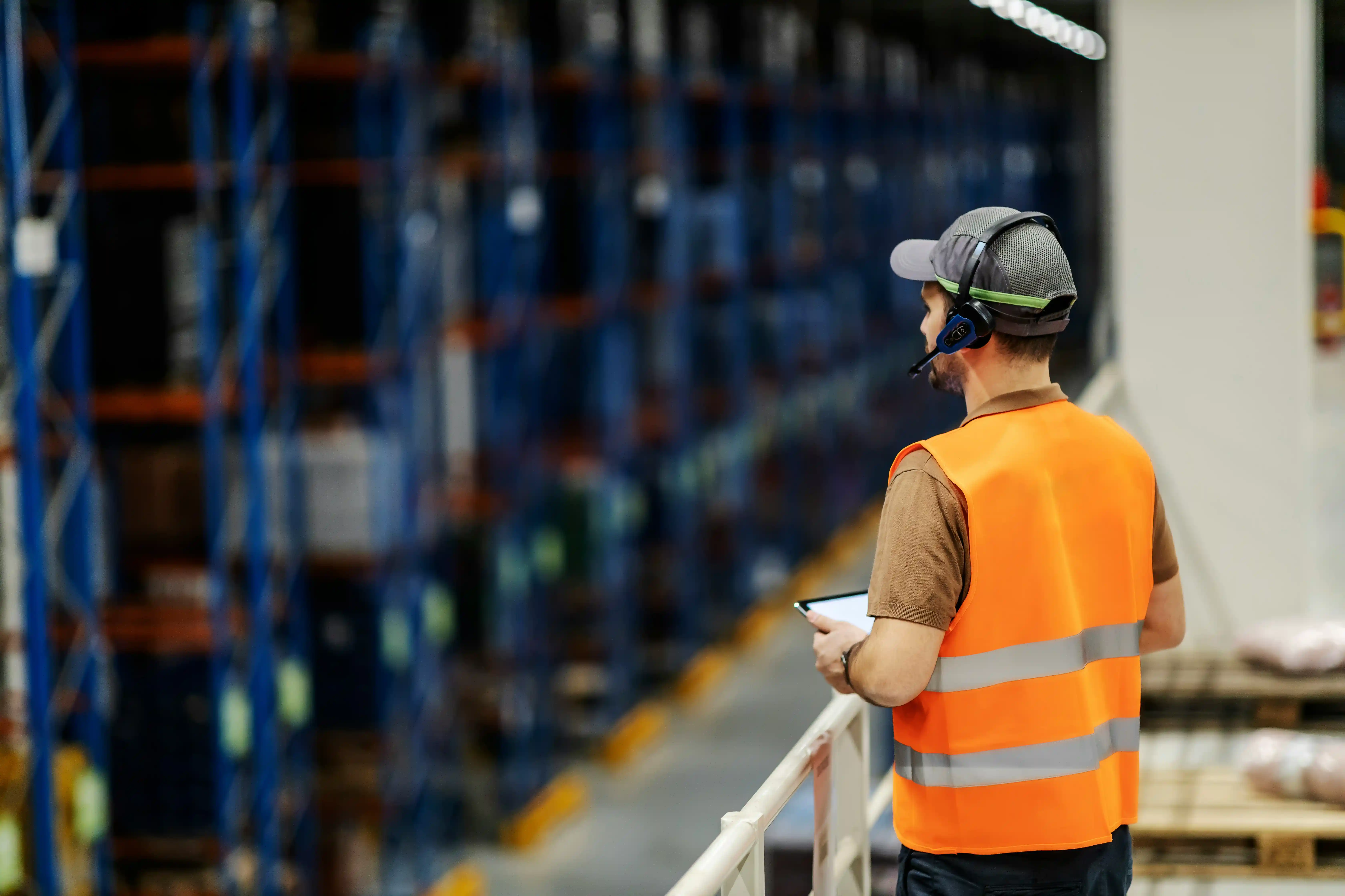 warehouse worker wearing mic overlooks a busy warehouse
