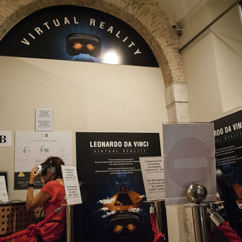 一位佩戴 VR 头显的人站在标有“达芬奇虚拟现实”的展示前,旁边有信息海报。