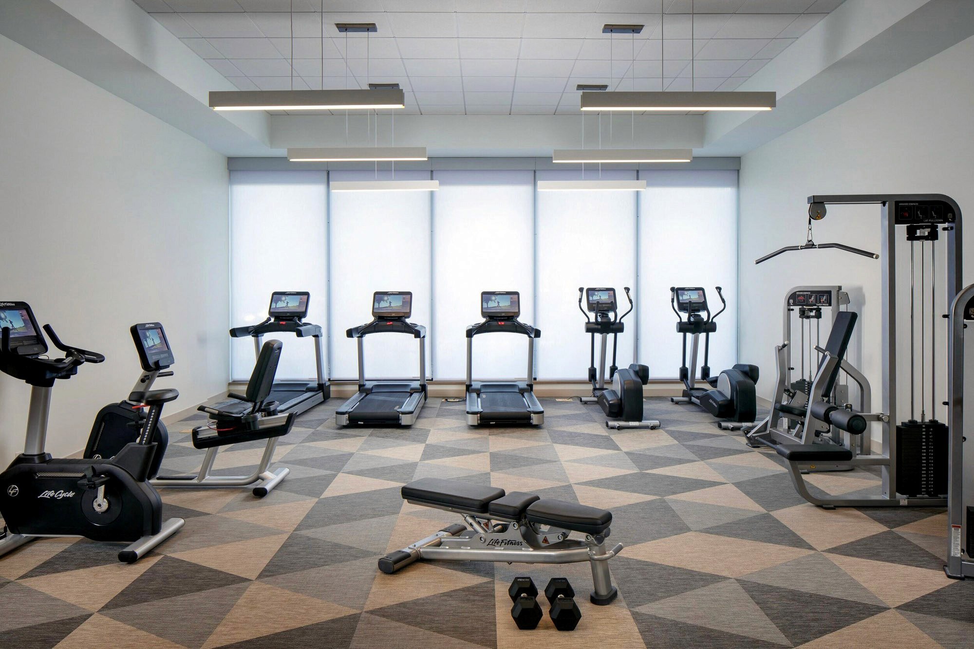 Hotel fitness center with treadmills, elliptical, exercise bikes, weight machine, bench