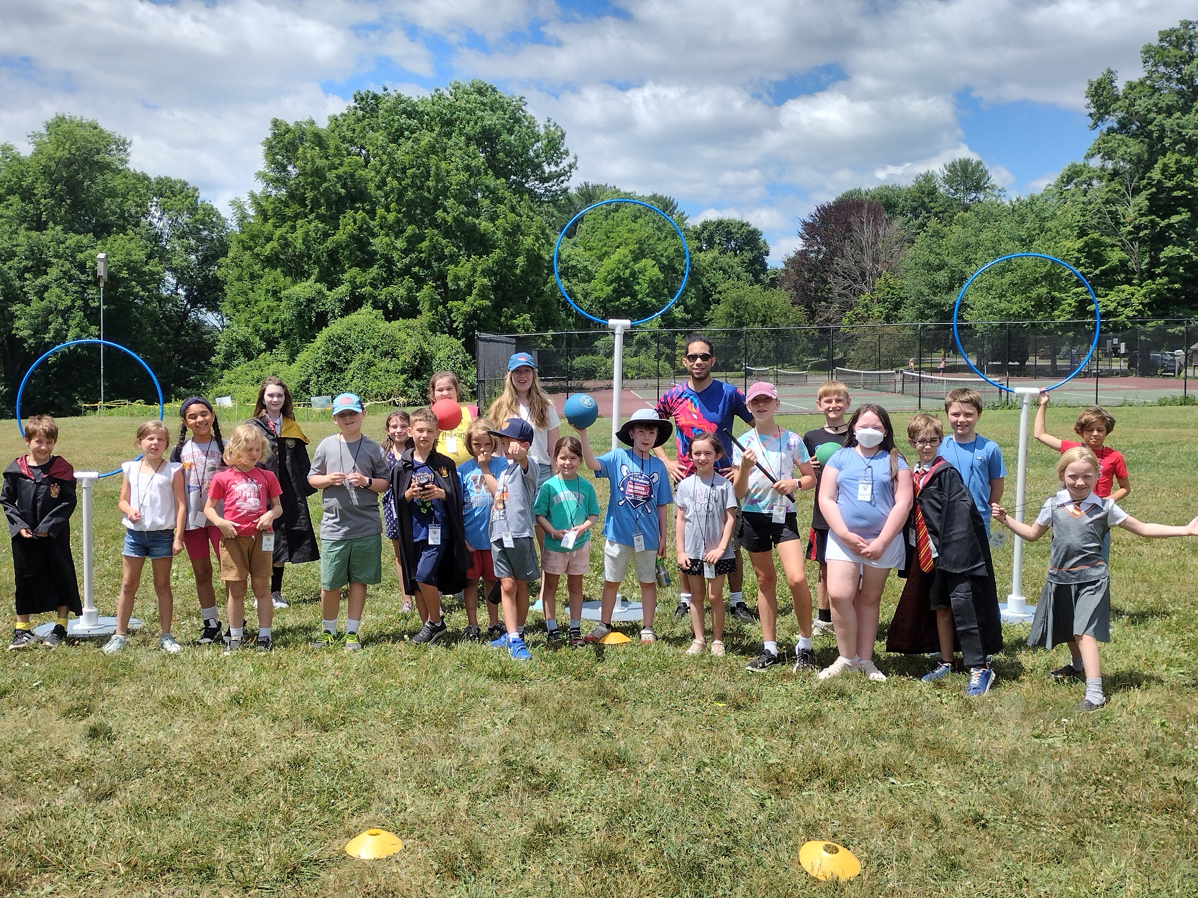 Children in athletic wear and Harry Potter-inspired outfits pose with organizers at a Kidditch event 