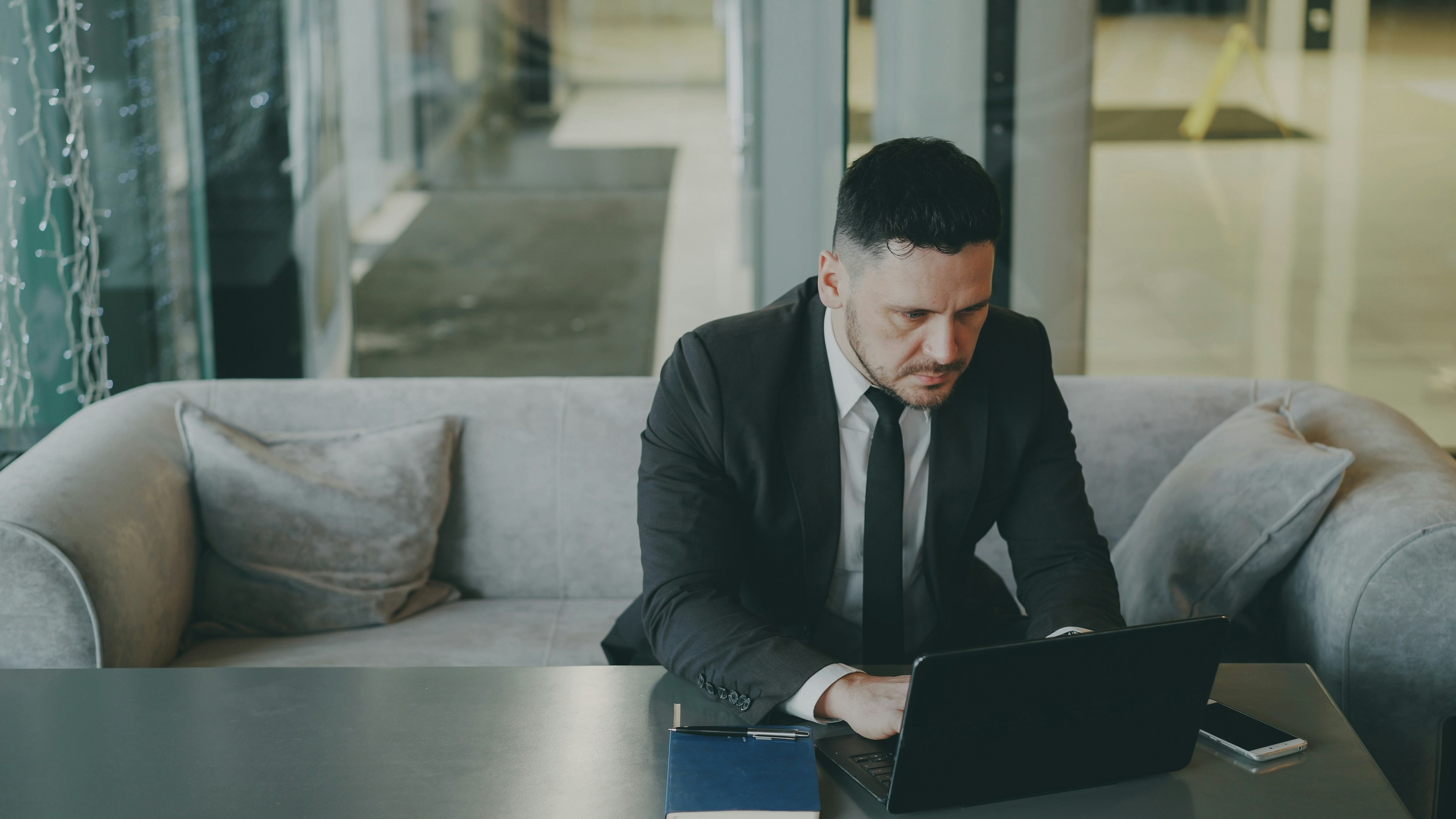 Man in suit working on laptop on sofa.