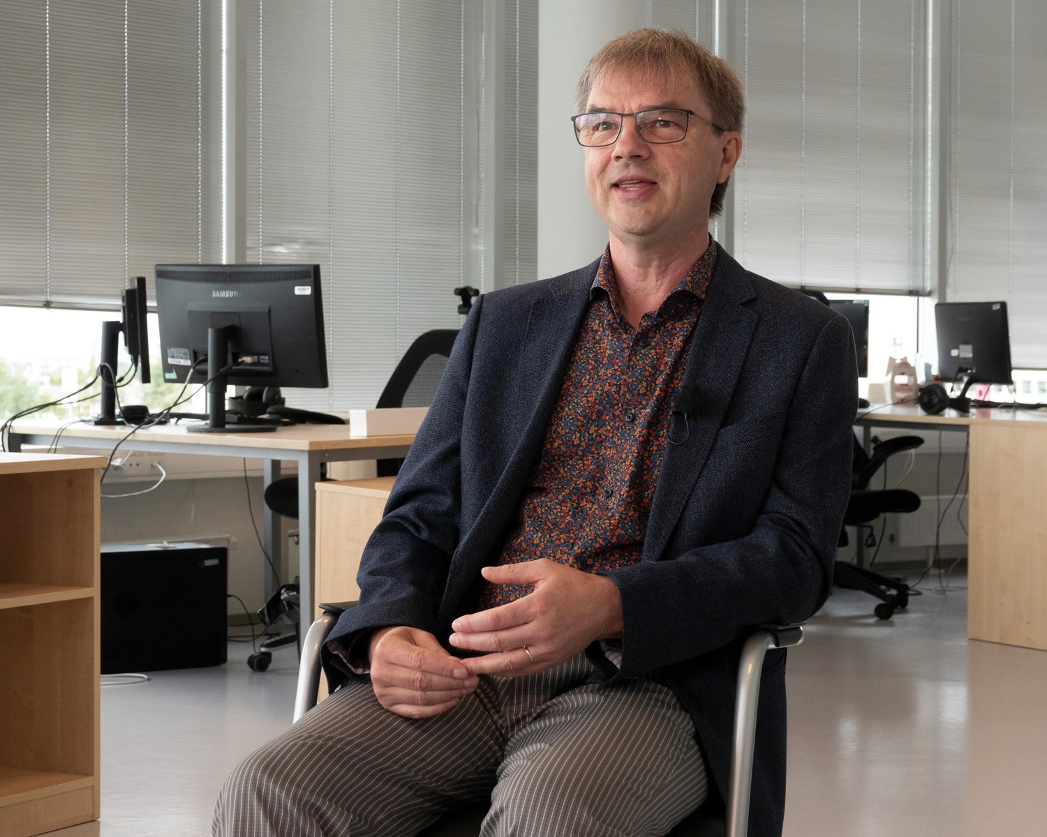 Mats Soomre seated in a Tallinn office, mid-conversation, smiling slightly. Contact page portrait.