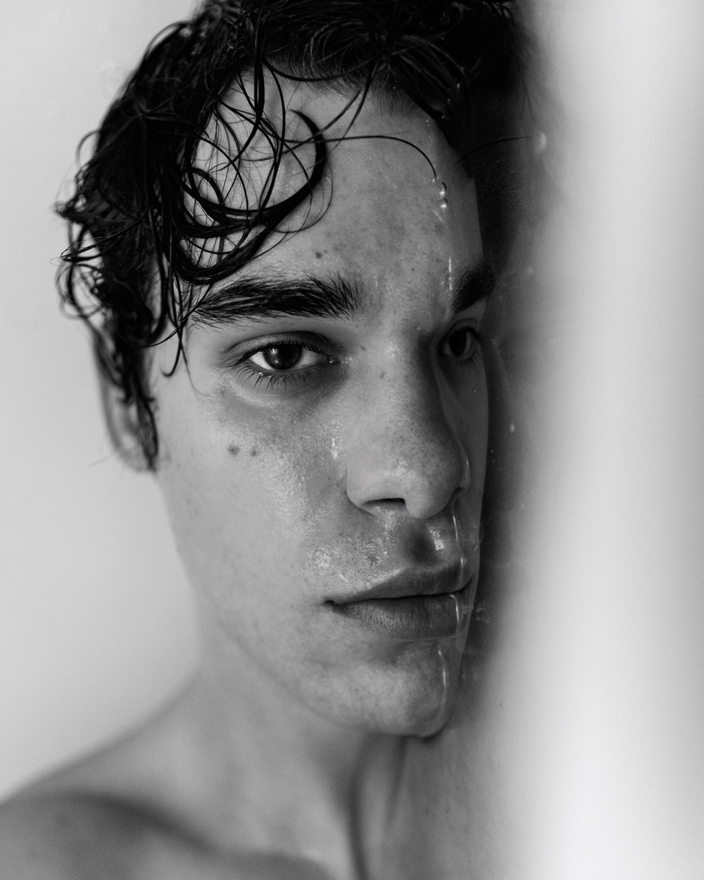 Green car under neon lights in a rainy city street