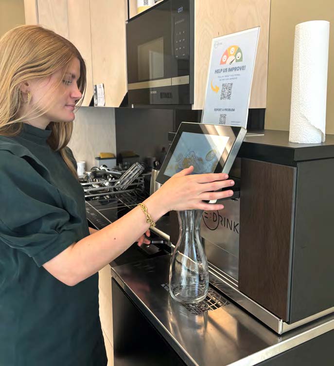 Frau macht sich im Büro ein frisches Getränk auf Knopfdruck