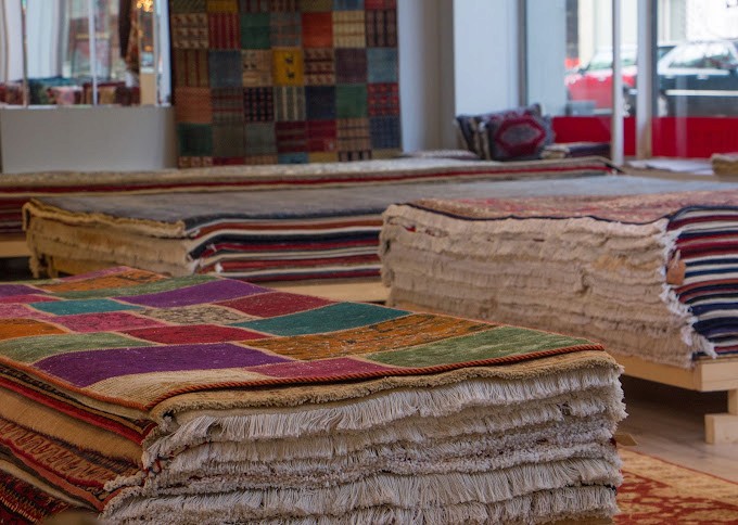 3 large pile of carpets are shown in the showroom of Heriz Tapijten in Rotterdam