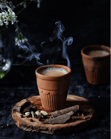 A rustic table set with various traditional pastries and a small bottle, surrounded by green foliage.