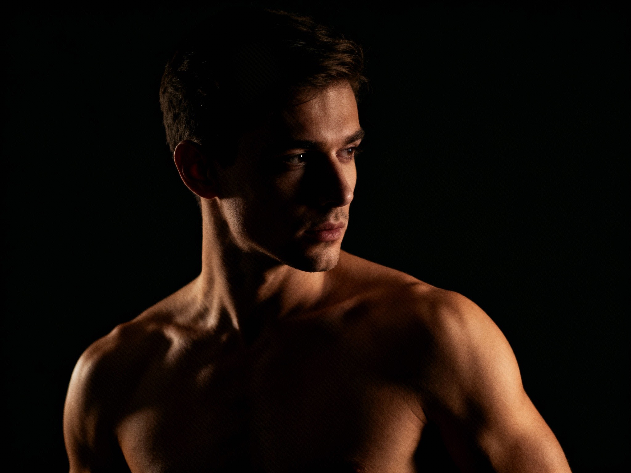 A fine-art studio portrait in a format featuring a poised dancer against a minimalist dark backdrop