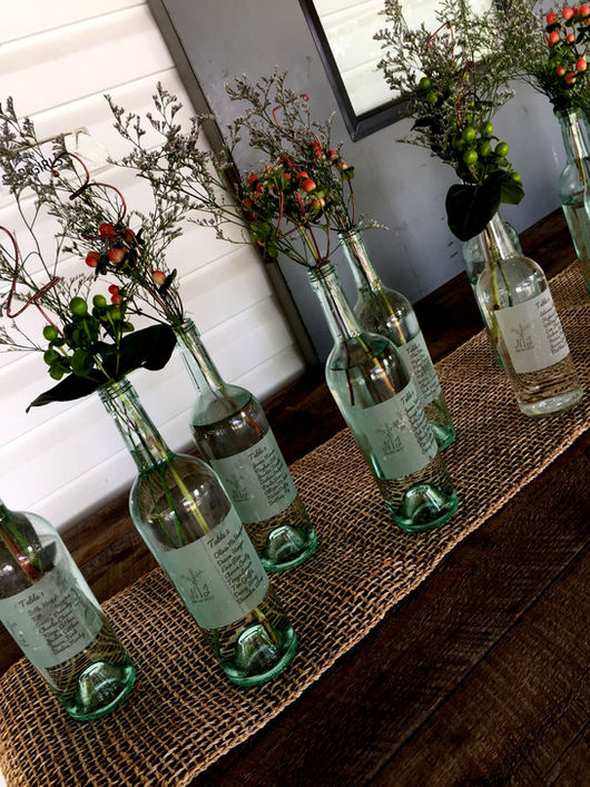 Glass bottle centerpieces with wildflowers and berries at Camp Lenox