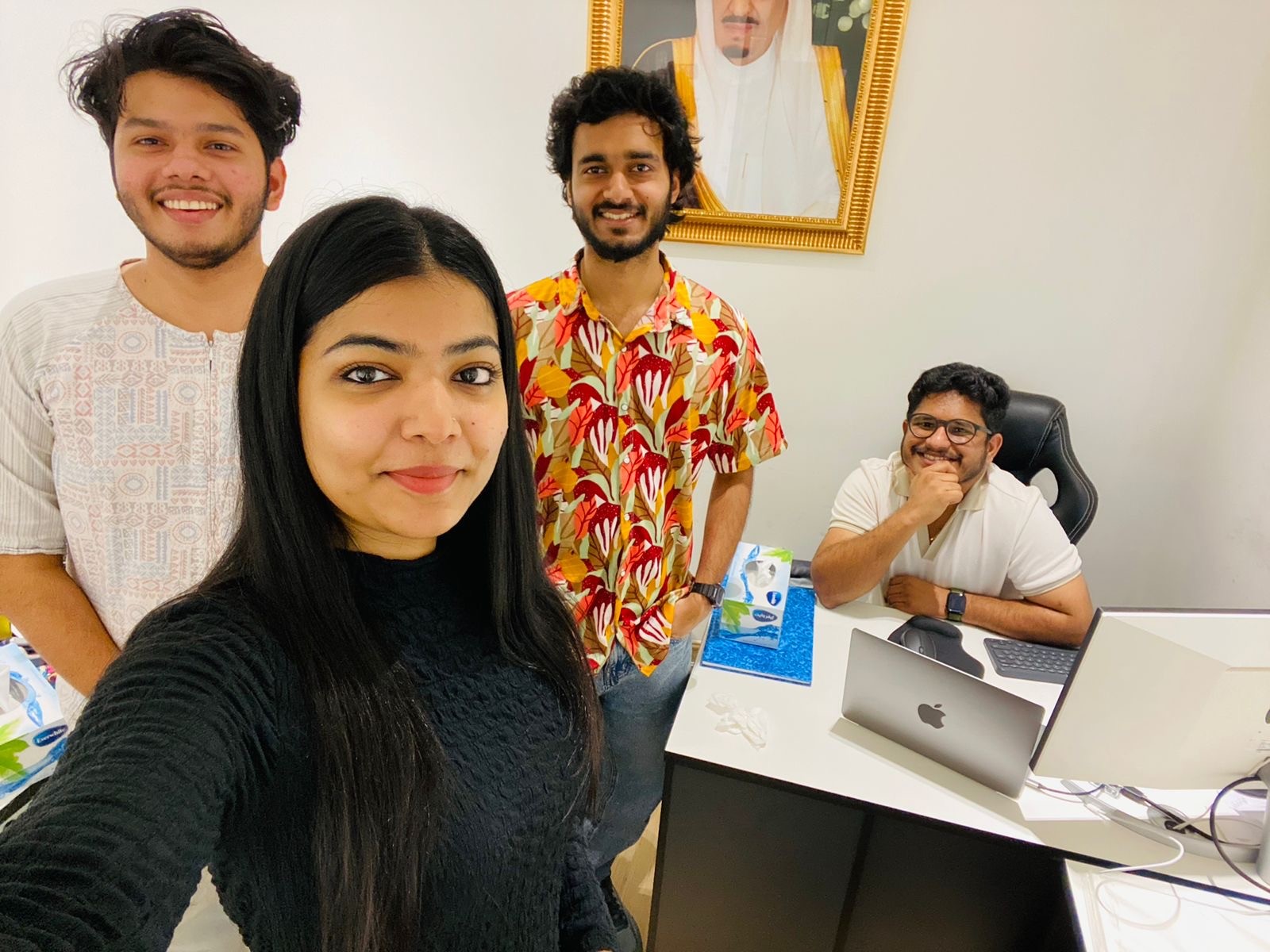 A large group photo of diverse team members gathered in an industrial-style space with arched ceiling.
