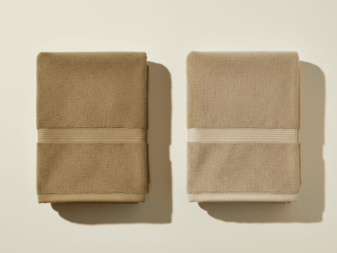 Two folded towels side by side showing a colourfastness comparison, one edge more faded than the other