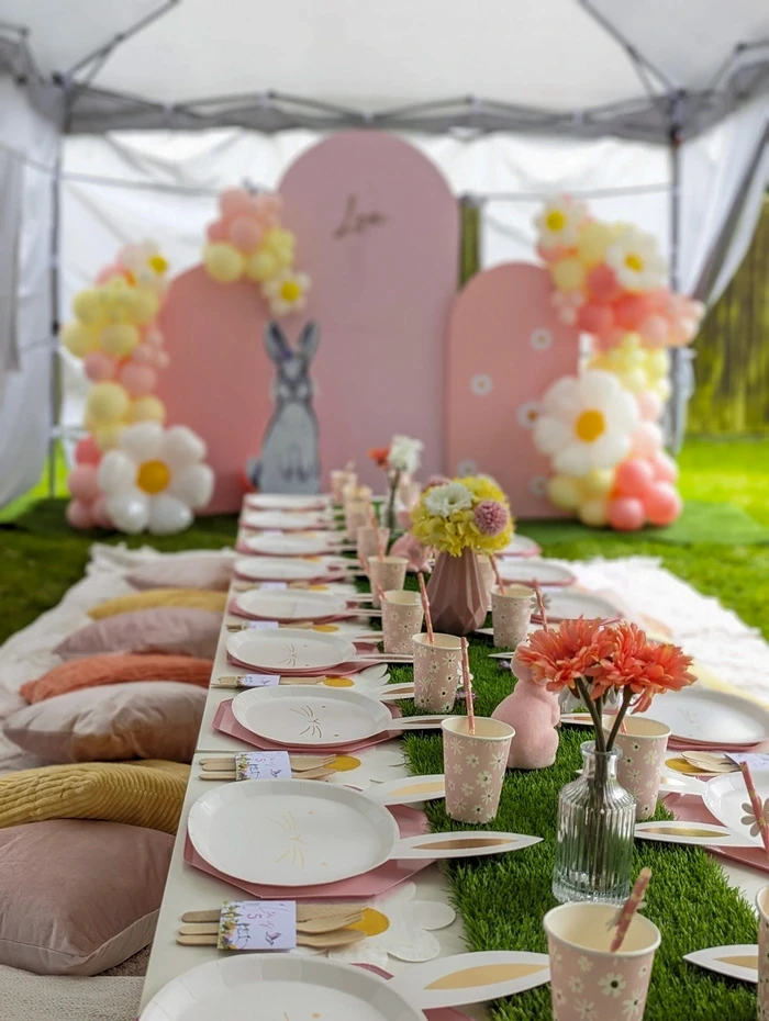 Elegant outdoor kids party table with peach flowers and balloon backdrop