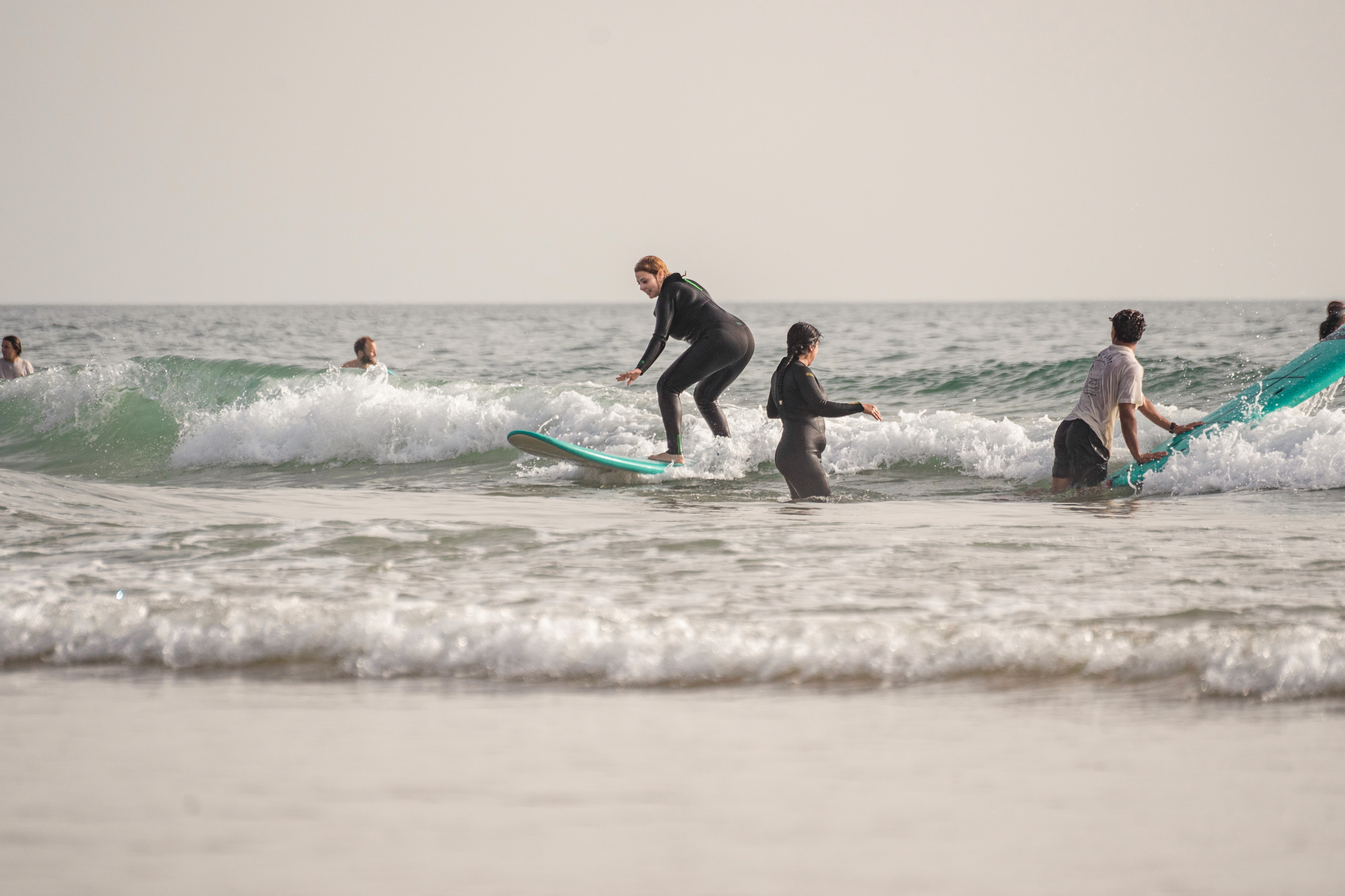 a group of people carrying surfboards on top of a beach