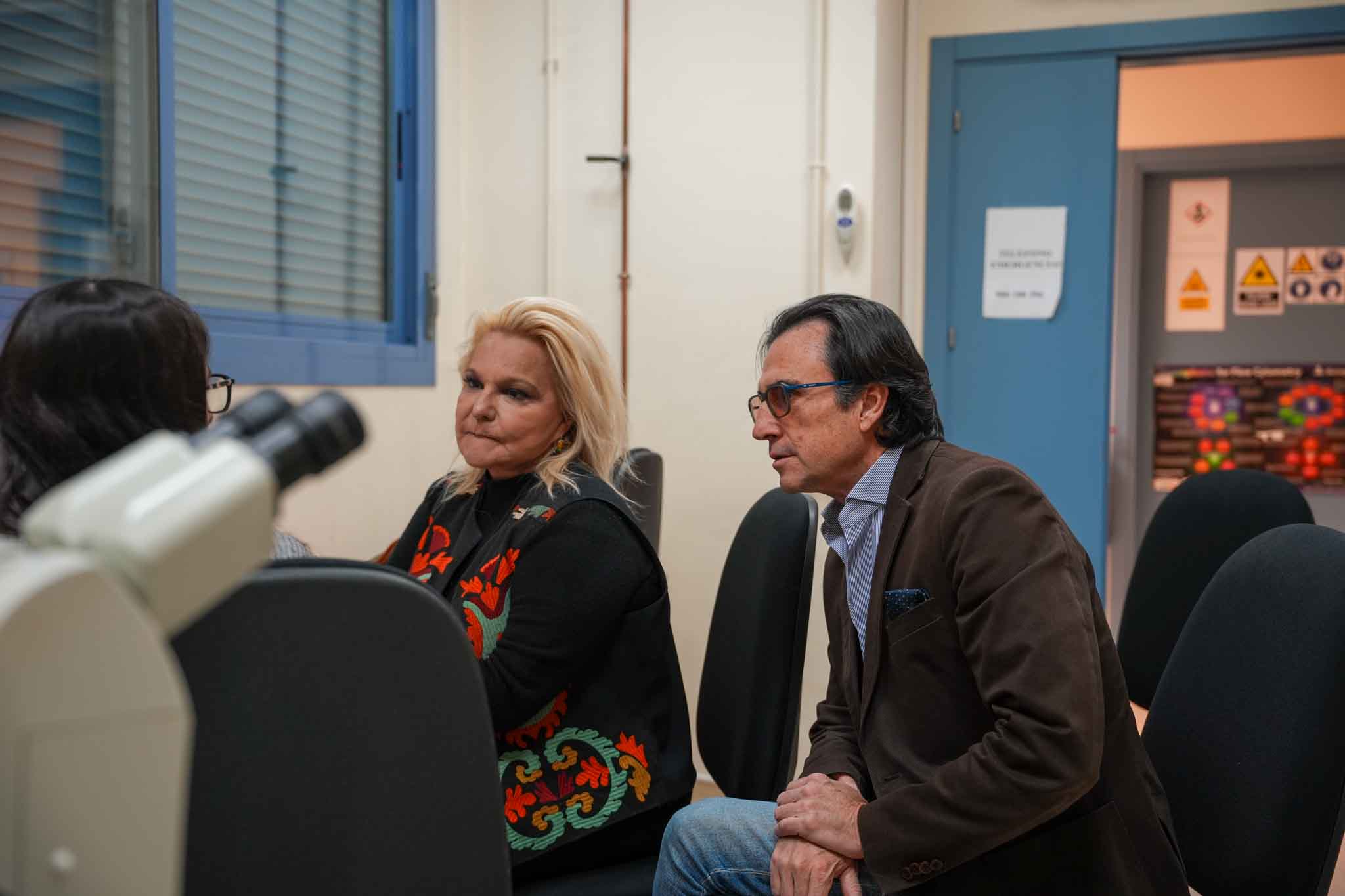 Stylish woman wearing an oversized cream quarter-zip sweatshirt and large sunglasses, looking to the side against a peach-colored wall.