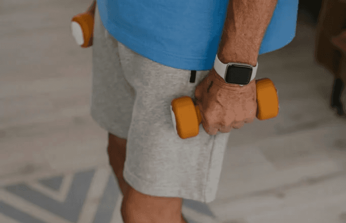waist level image of older man exercising with light weight dumbells