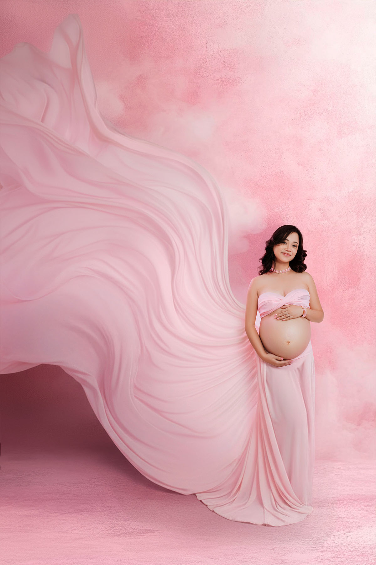 Pregnant woman with flowing fabric in Bloom N’ Baby Studio — graceful and artistic maternity photo.