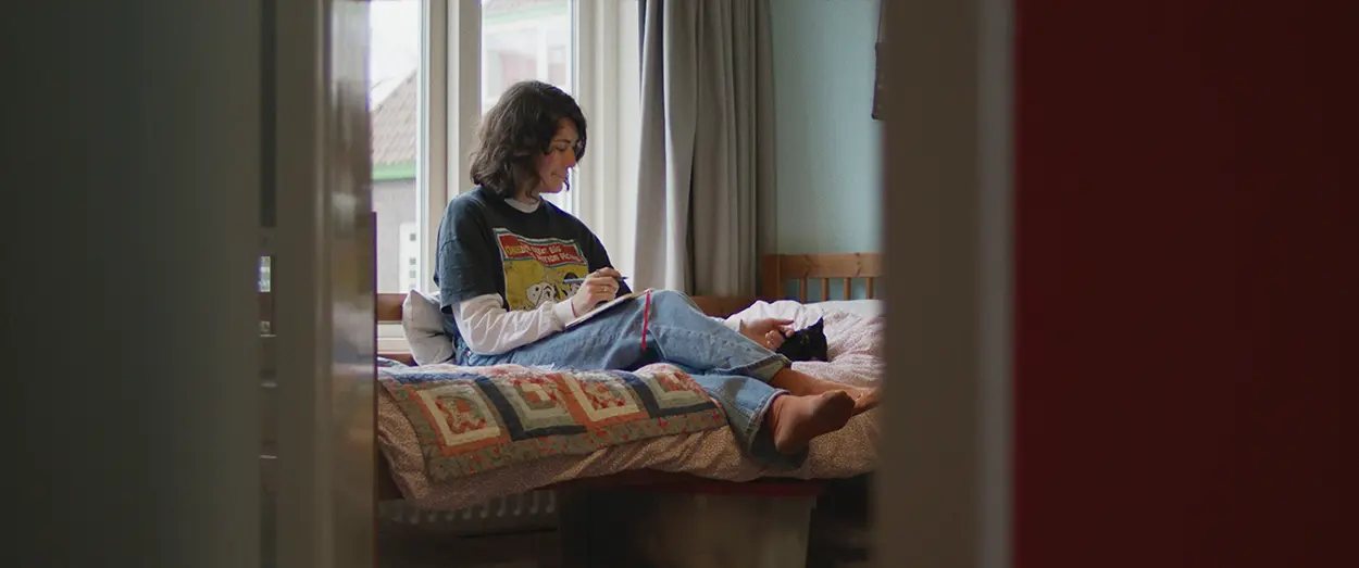 Girl sitting on bed in her room looking at a book