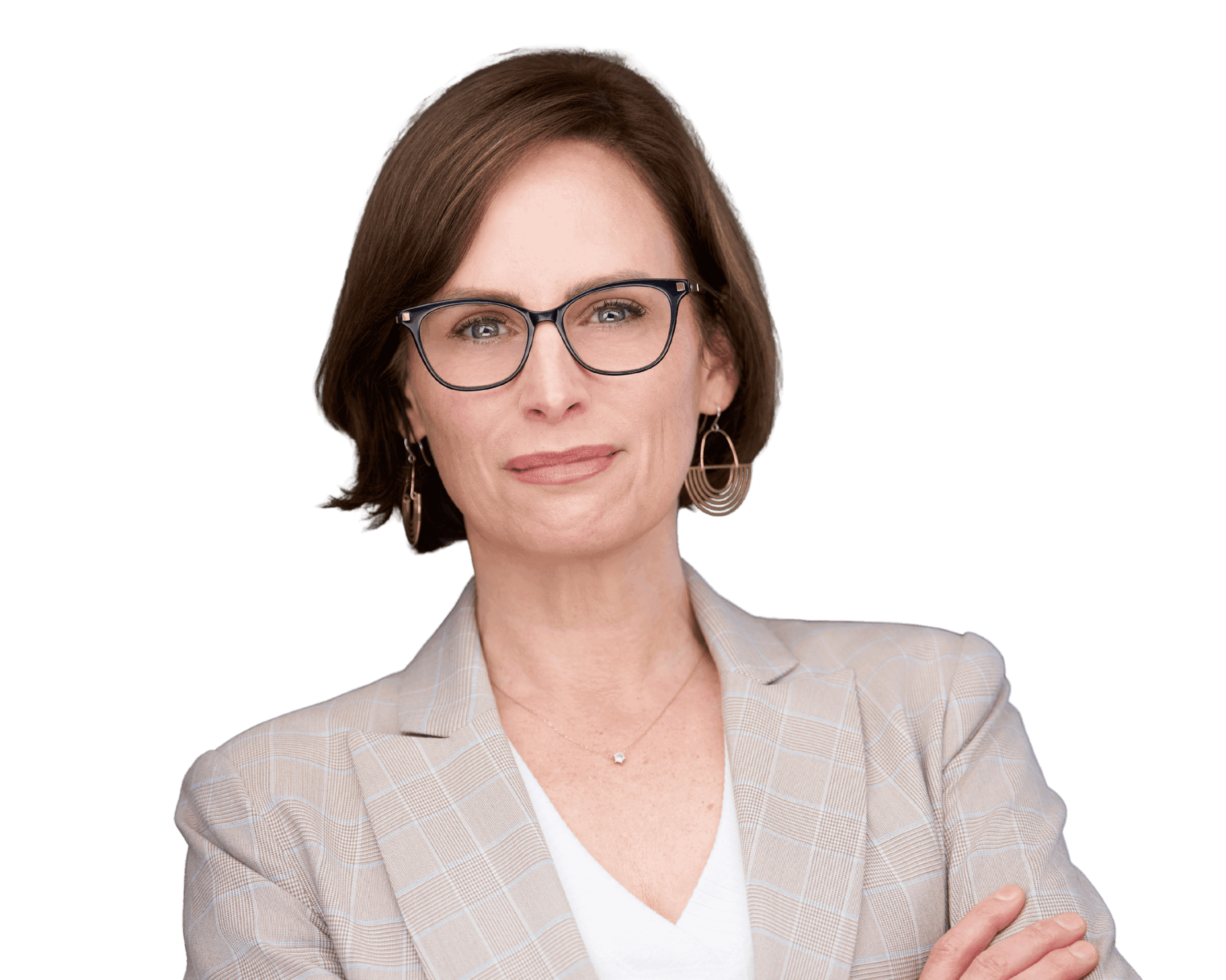 A confident person with short brown hair and glasses, wearing a light plaid blazer over a white shirt, stands with arms crossed against a plain background.
