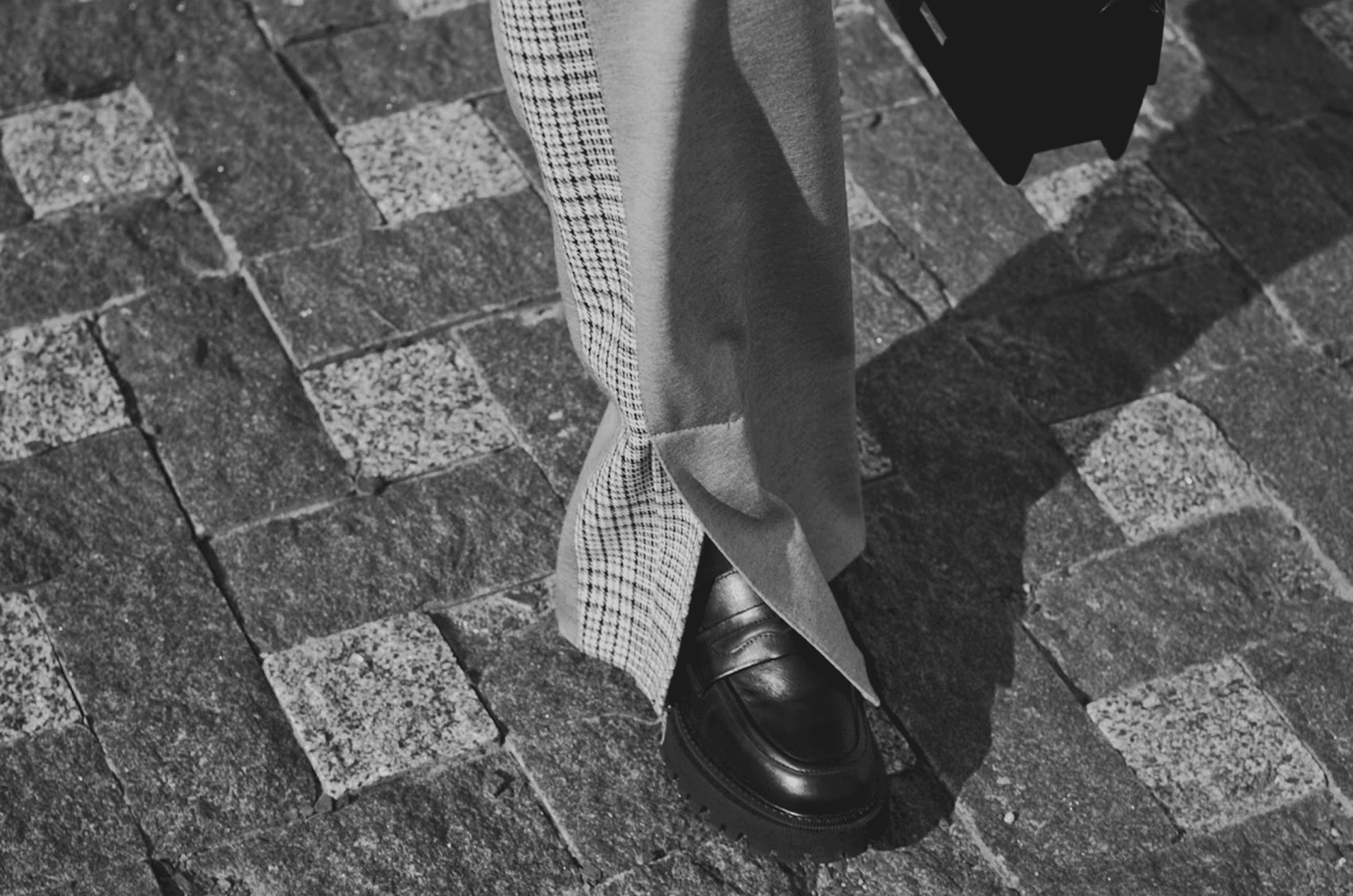 Person in checkered pants and loafers walking on cobblestone pavement with briefcase, symbolizing professional B2B teams partnering with top LinkedIn marketing agencies for growth in 2026