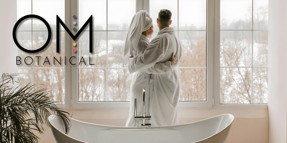 A couple in bathrobes enjoys a serene moment together by the window, reflecting OM Botanicalโs holistic skincare approach.