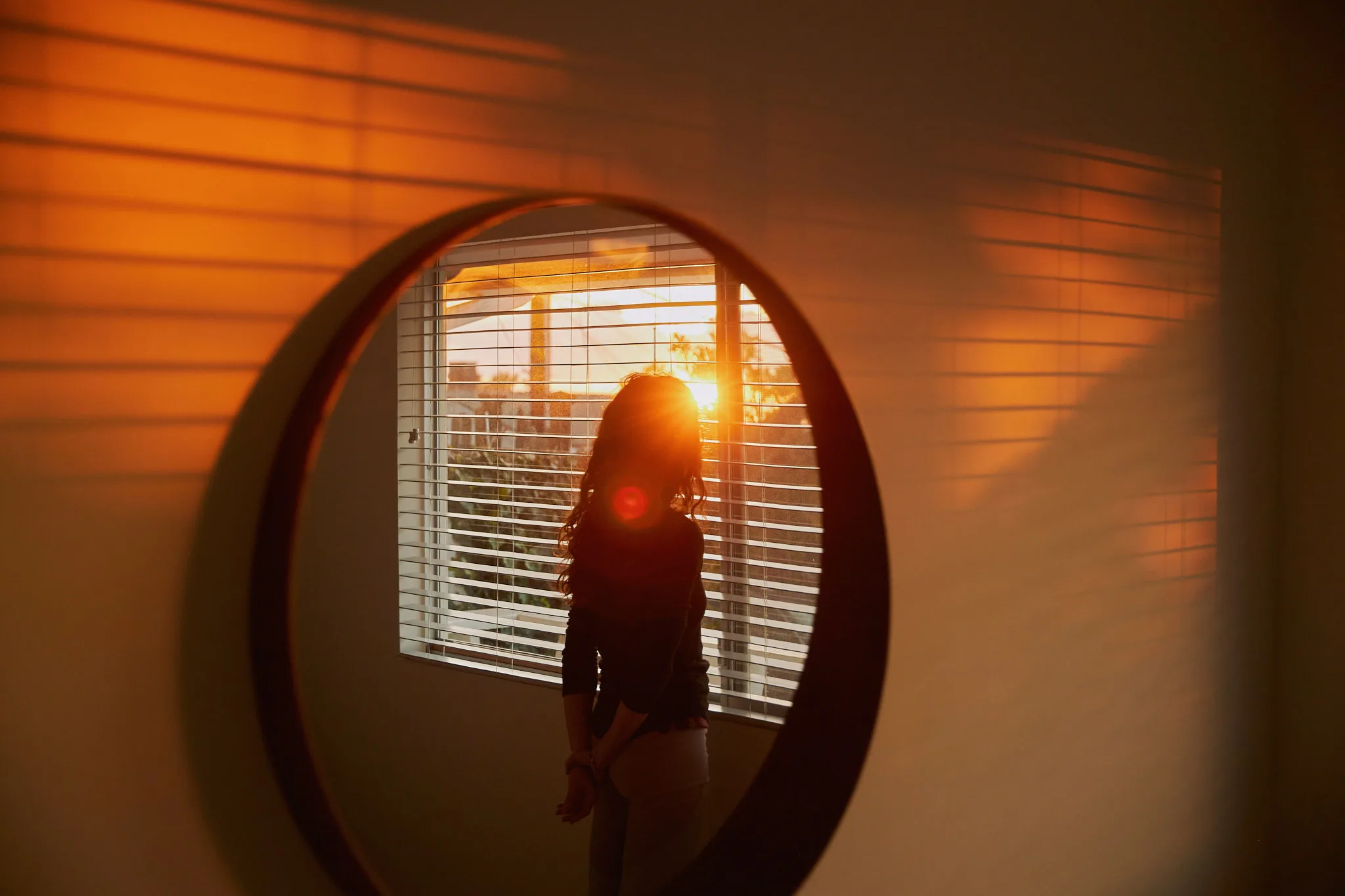 woman silhouetted in round mirror at sunset — portrait photography by Tom Kubik