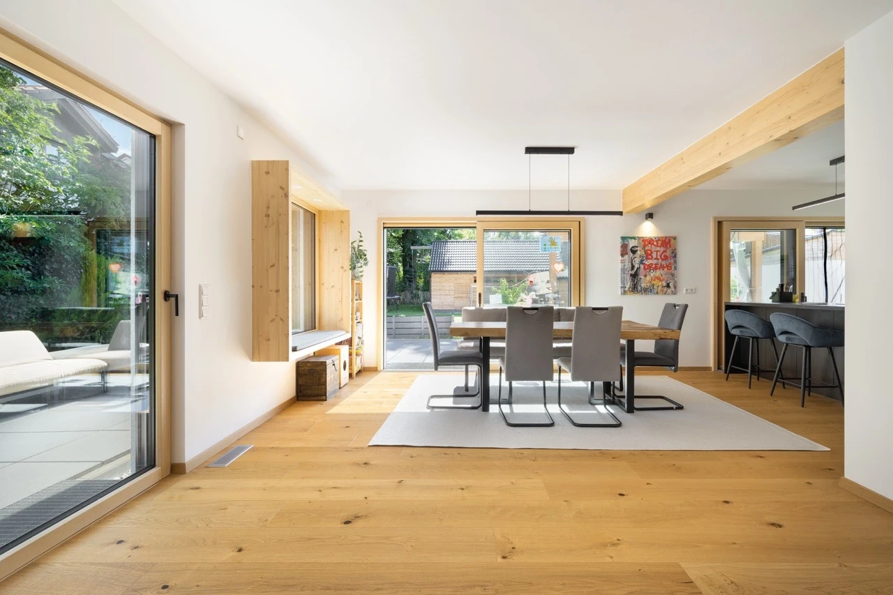 Modern dining area with wooden floors, large windows, and a table for six.