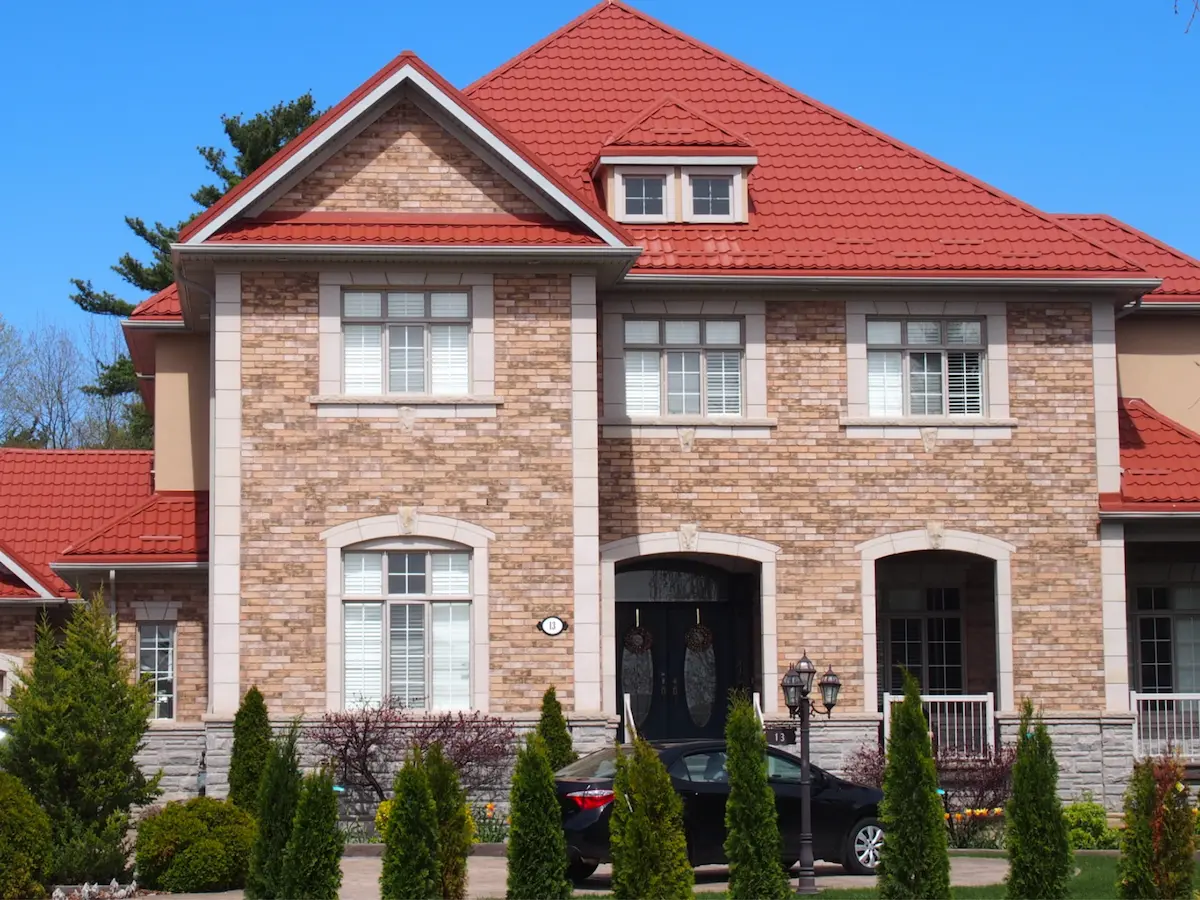  Toiture en tuiles métalliques rouges sur maison résidentielle en briques avec lucarne