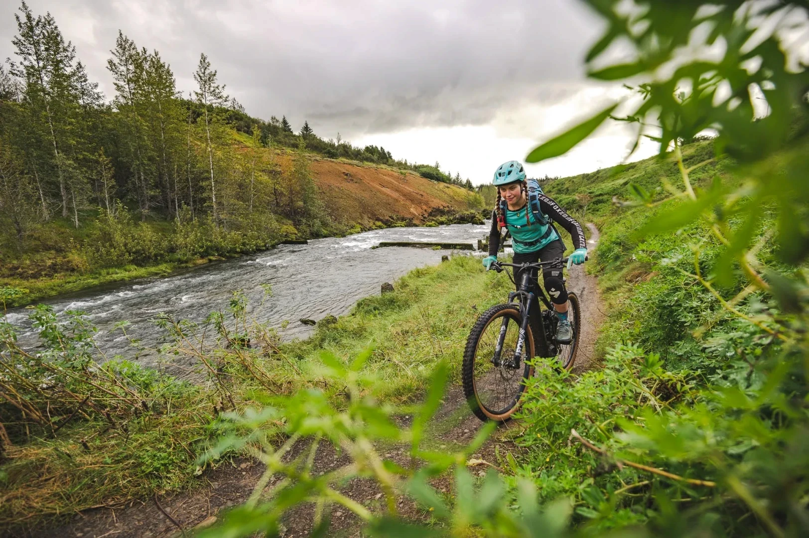 girl rides bike alongside a river 