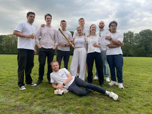 group of people standing together in light shirts and looking and posing to the camera. Beautifull nature park background. One man is laying on the grass in a friendly pose - posing for the photo