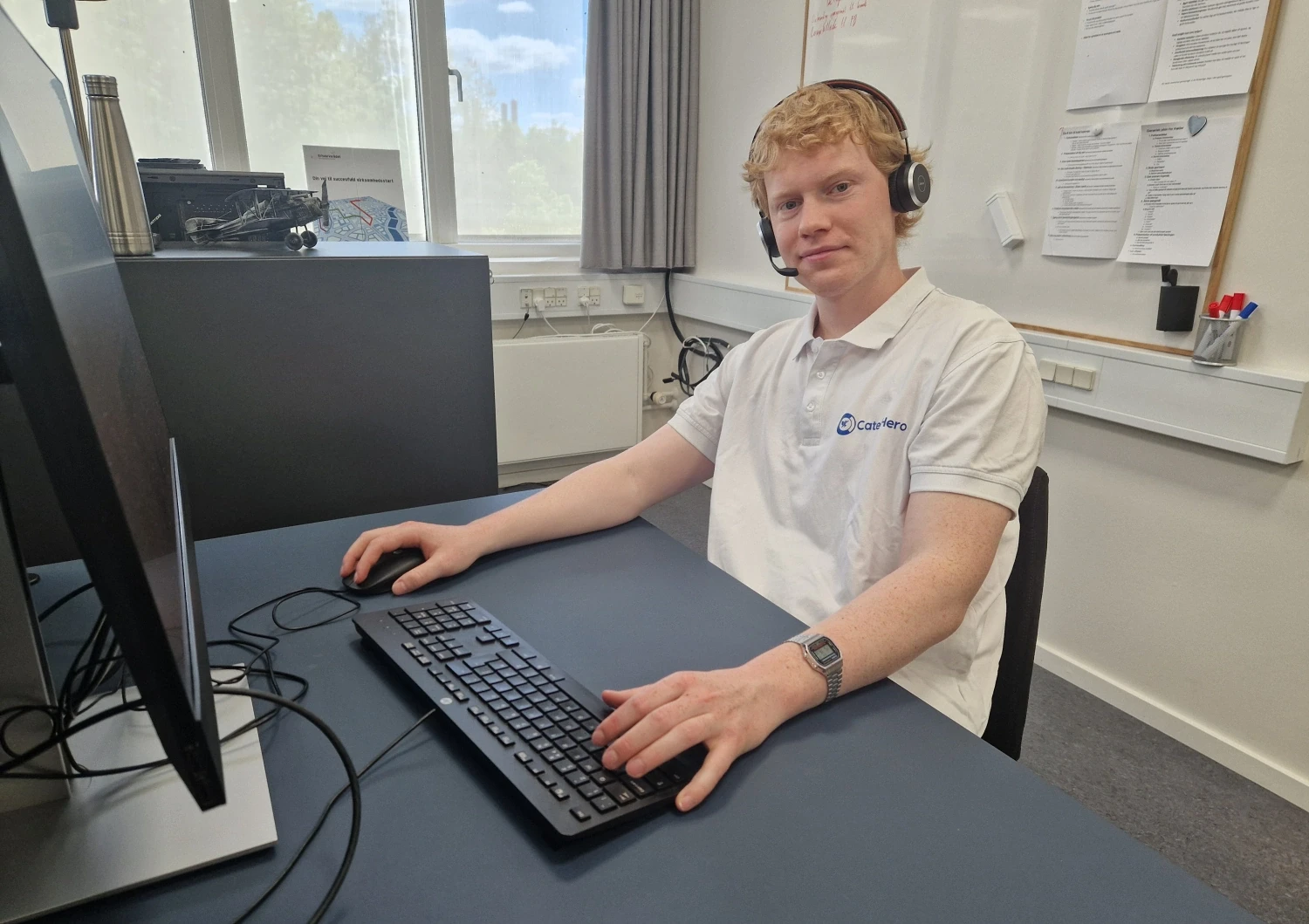 Billede af Mads med headset ved en PC, som udfører kundeservice