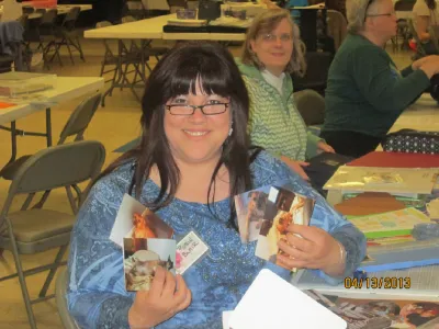 Scrapbooker holding up photos she is sorting for a custom album