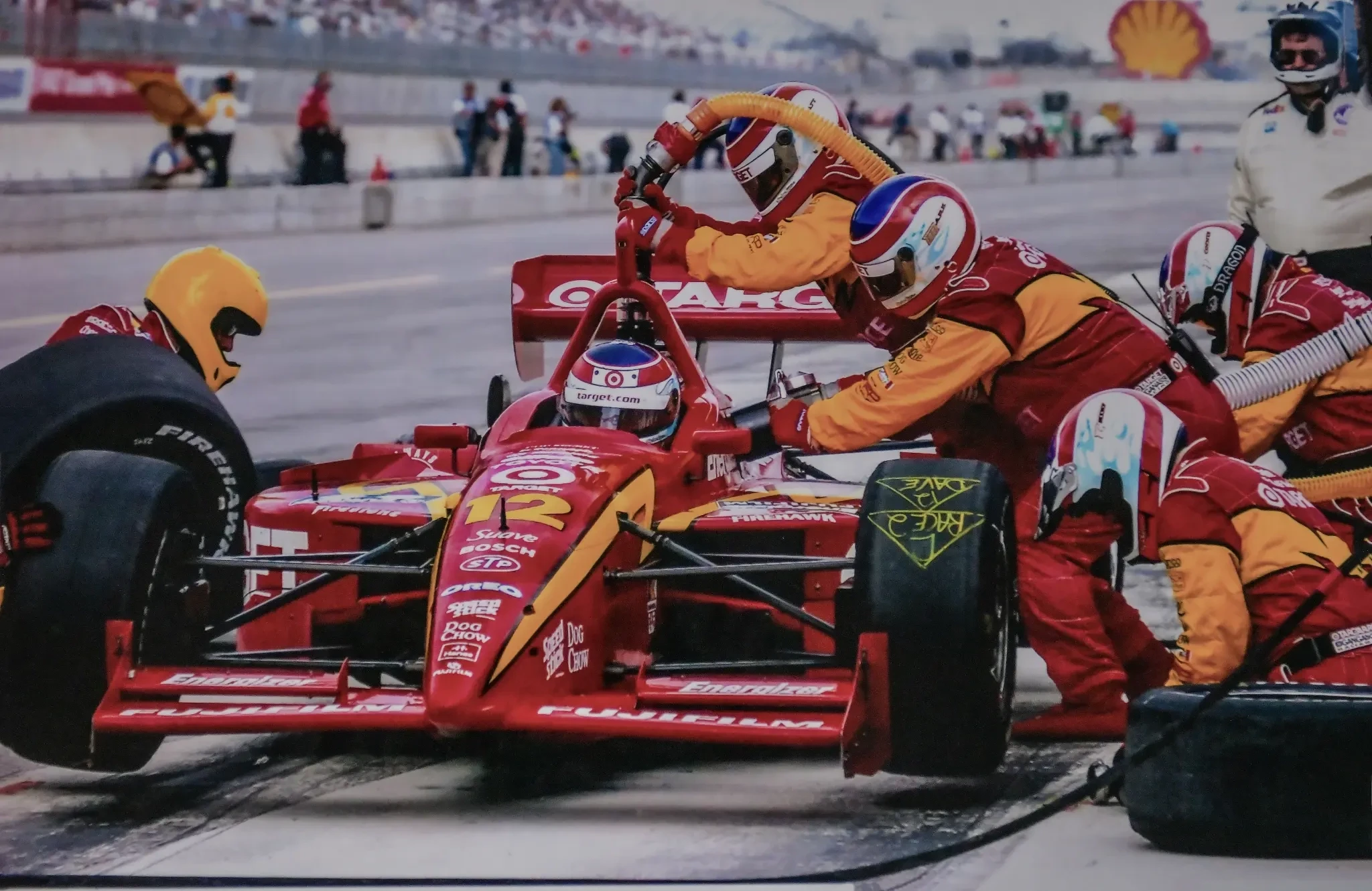 Formula racing pit crew changing a red race car’s tires during a pit stop.