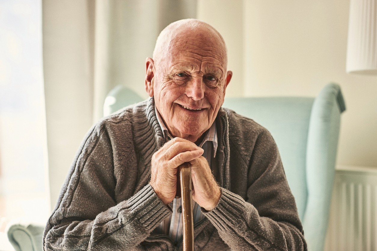 A smiling doctor with glasses and stethoscope stands arms crossed.
