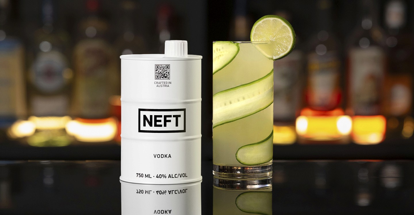 A NEFT Barrel and a glass of Cucumber Gimlet on a bar counter.