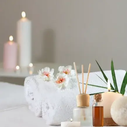 Przytulne detale gabinetu Belleza – białe ręczniki, świece i kwiaty symbolizujące relaks, aromaterapię i troskę o każdy szczegół.