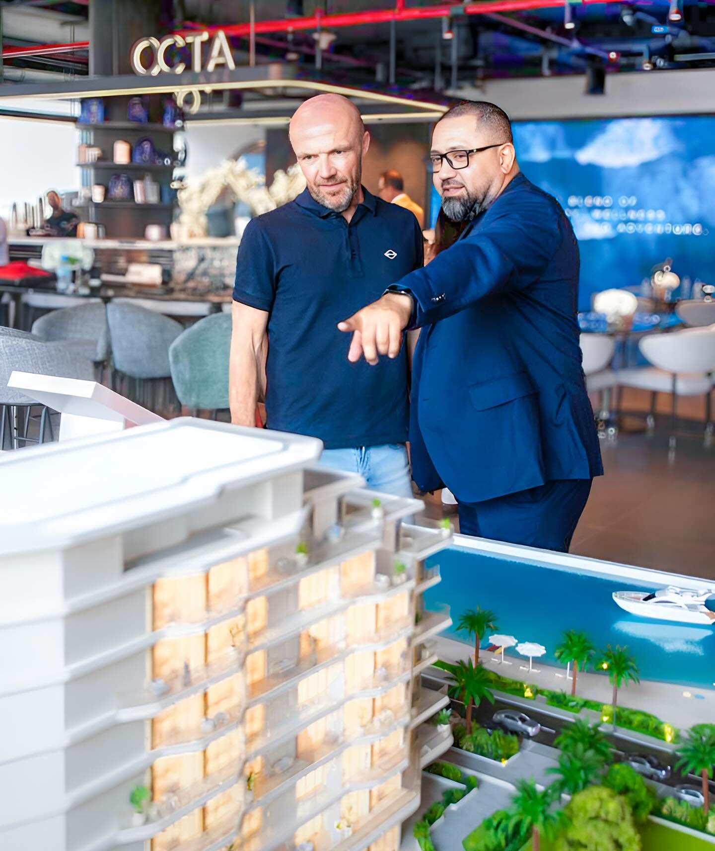 Black-and-white party photo of a smiling man in a check blazer among a crowd.