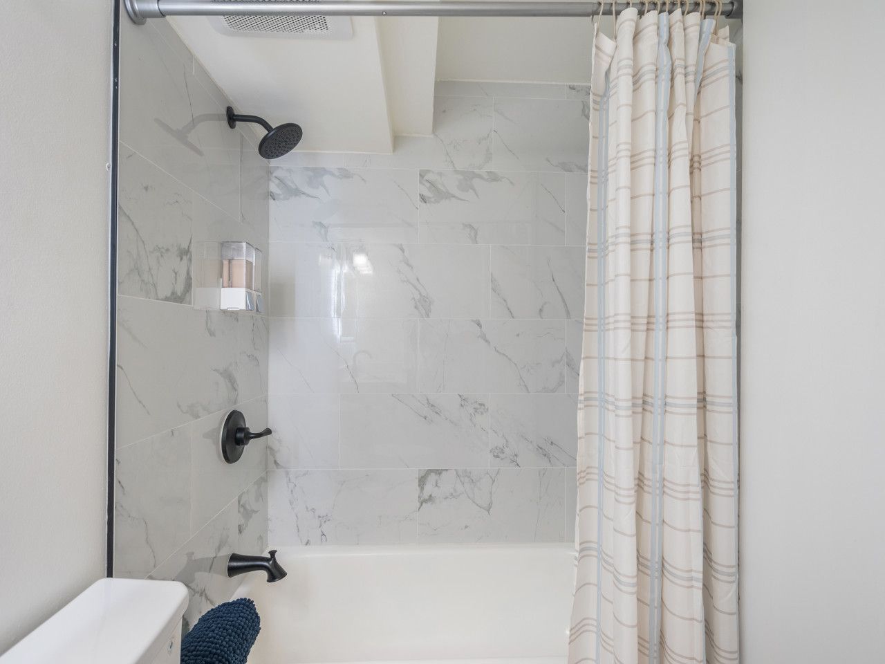 Marble-look tiled tub-shower with matte-black fixtures