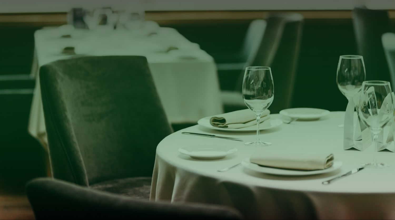 A clean, elegant restaurant dining room featuring set tables with white linens and glassware.