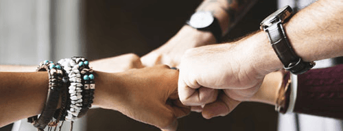Stock image of several fists all meeting in the middle