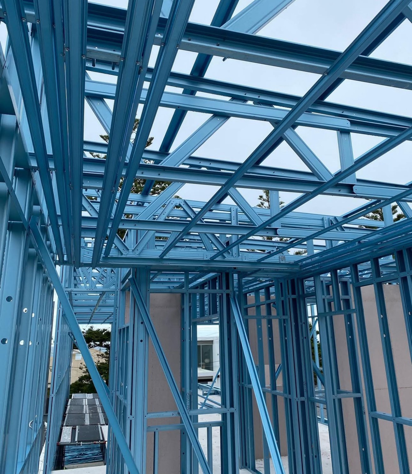 A smiling young man with crossed arms, wearing a plaid shirt and white t-shirt, poses against a dark background.