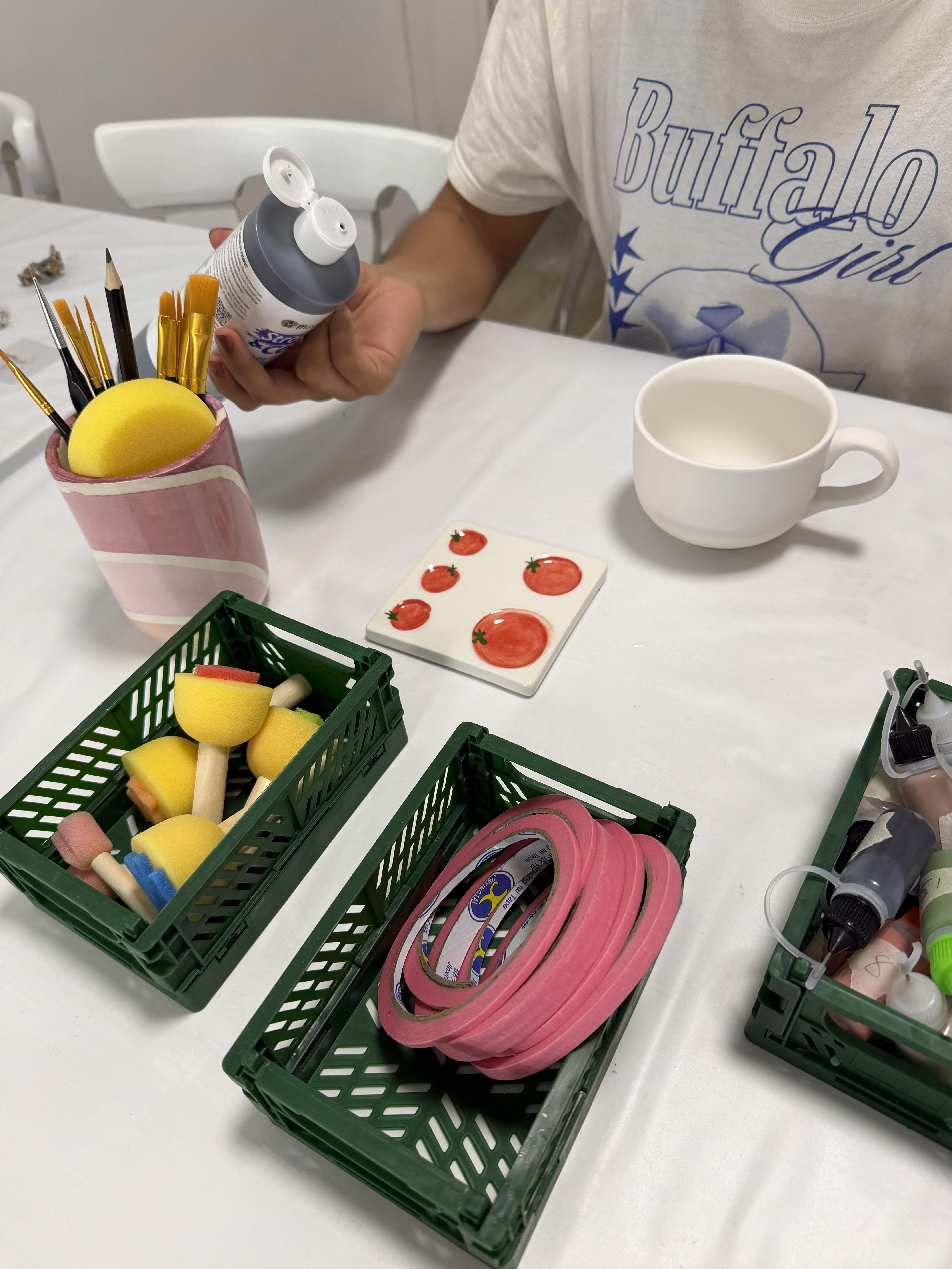 Hands painting ceramics at a worktable