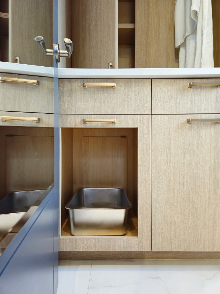 Image of Light wood cabinetry with gold handles and built-in pull-out dog wash station by KHD Homes.