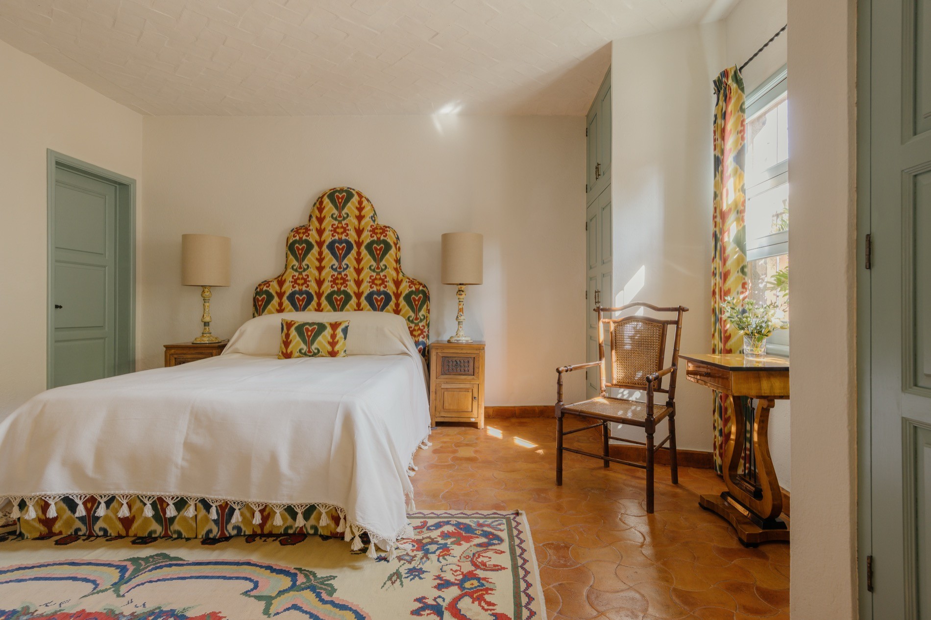 La Residencia guest bedroom with colorful ikat headboard and sage green closets