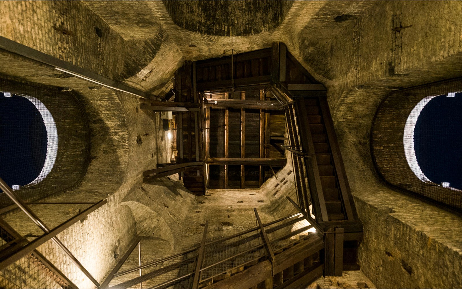 Interior view of a historic tower in Torino, featuring wooden stairs and brick walls.
