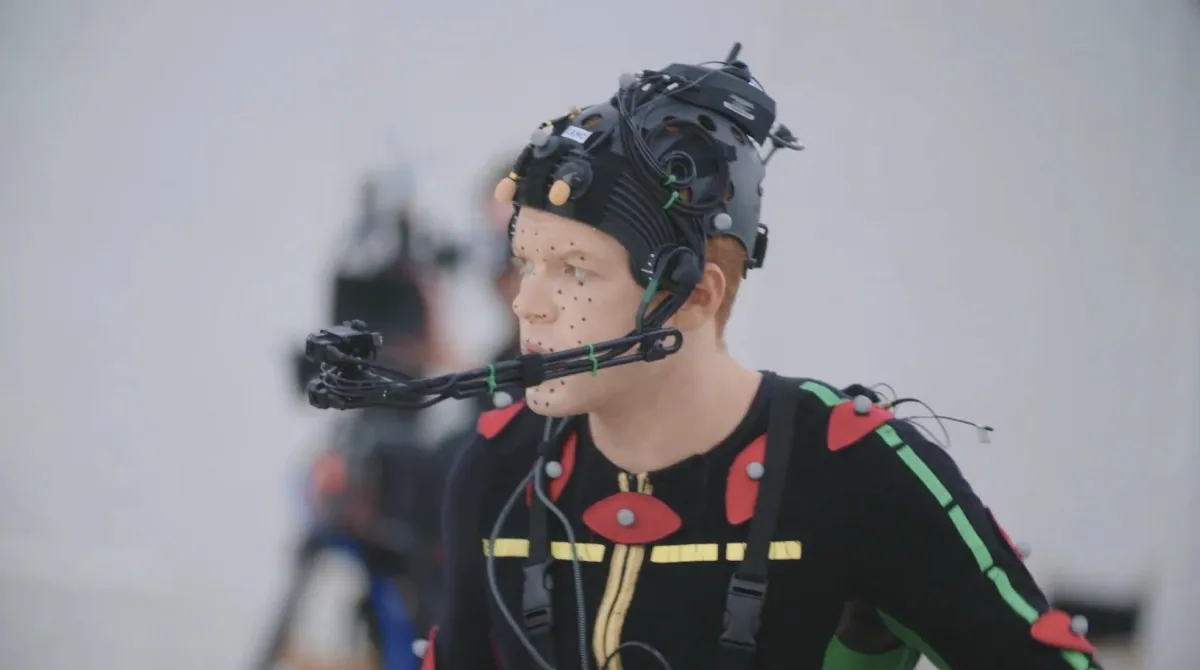 Cameron Monaghan behind the scenes of Jedi: Fallen Order wearing a motion capture suit covered in dots with a camera rig on his head