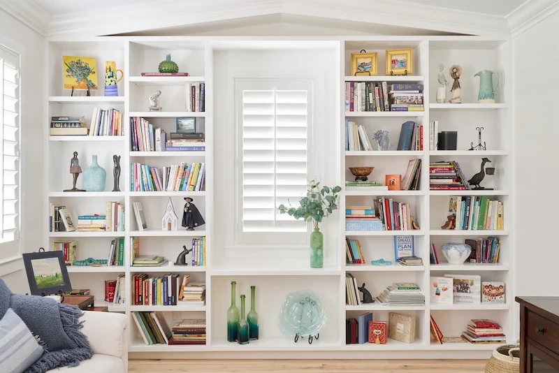 Wide shot of a home library, with a focus on the extensive bookcase, blending functionality with contemporary coastal design from the Ladera Ranch Remodel Project. Photo by Todd Huge.