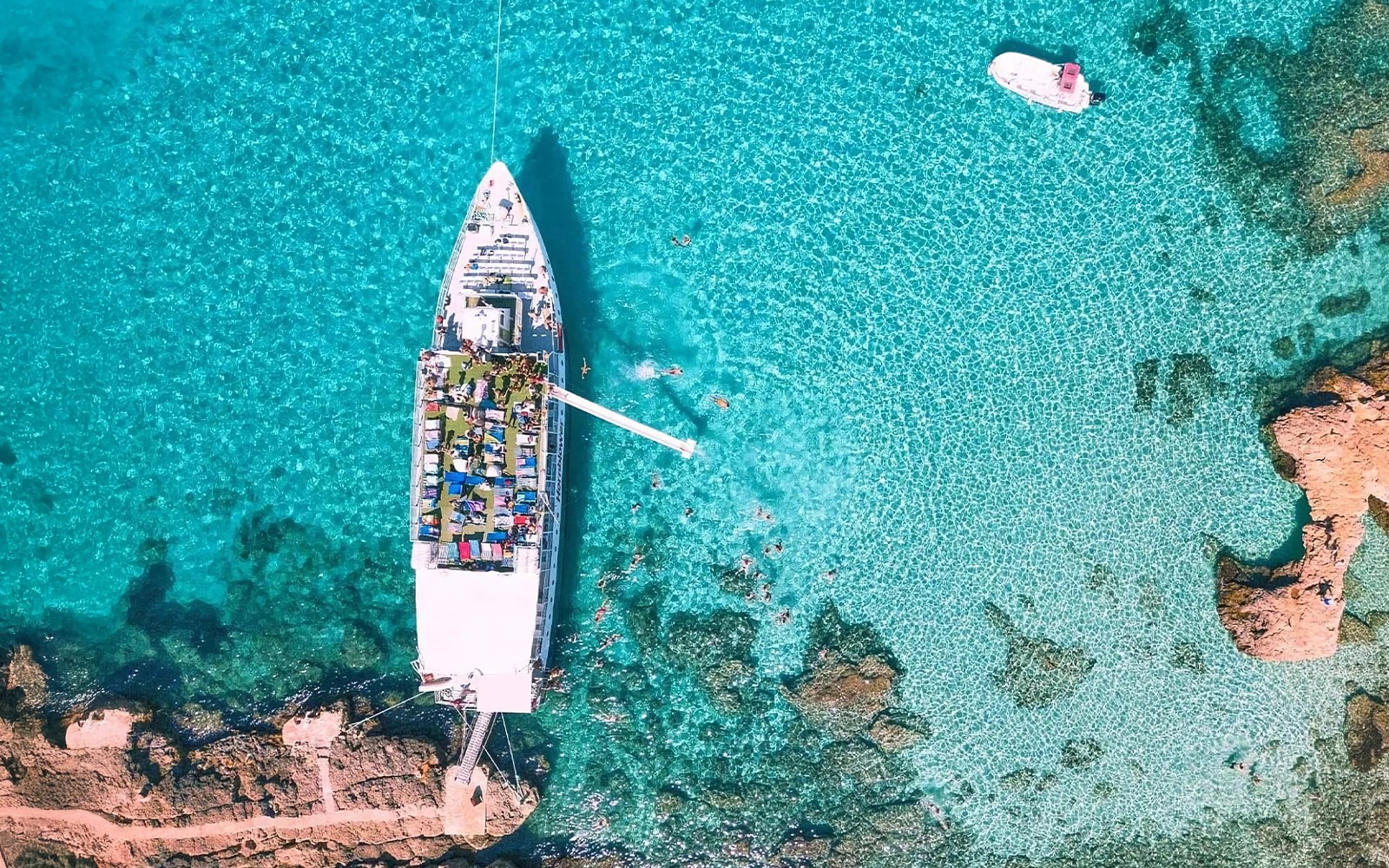 Cruise ship docked at Blue Lagoon, Malta, surrounded by clear turquoise water.