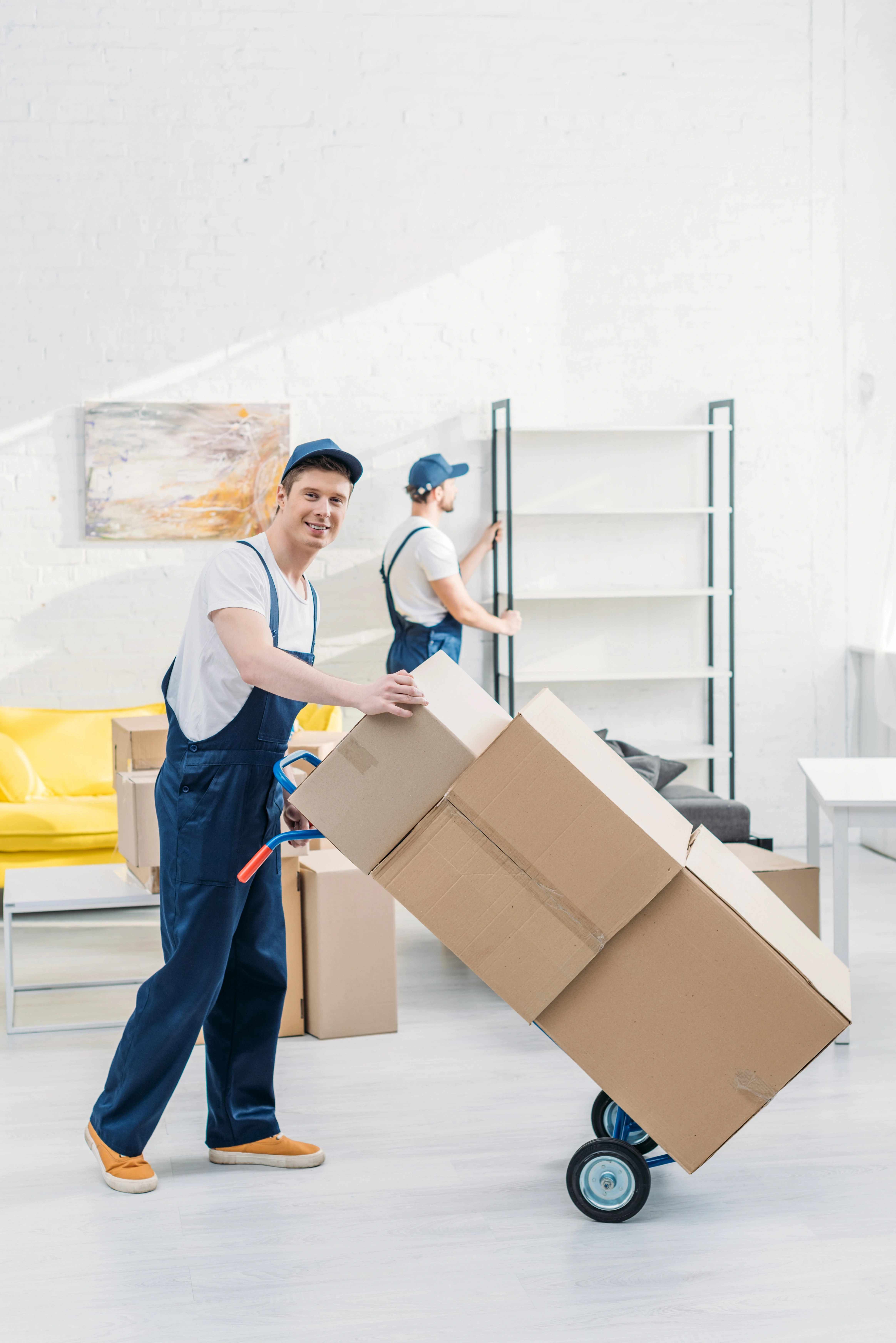 two-movers-uniform-transporting-cardboard-boxes-furniture-apartment