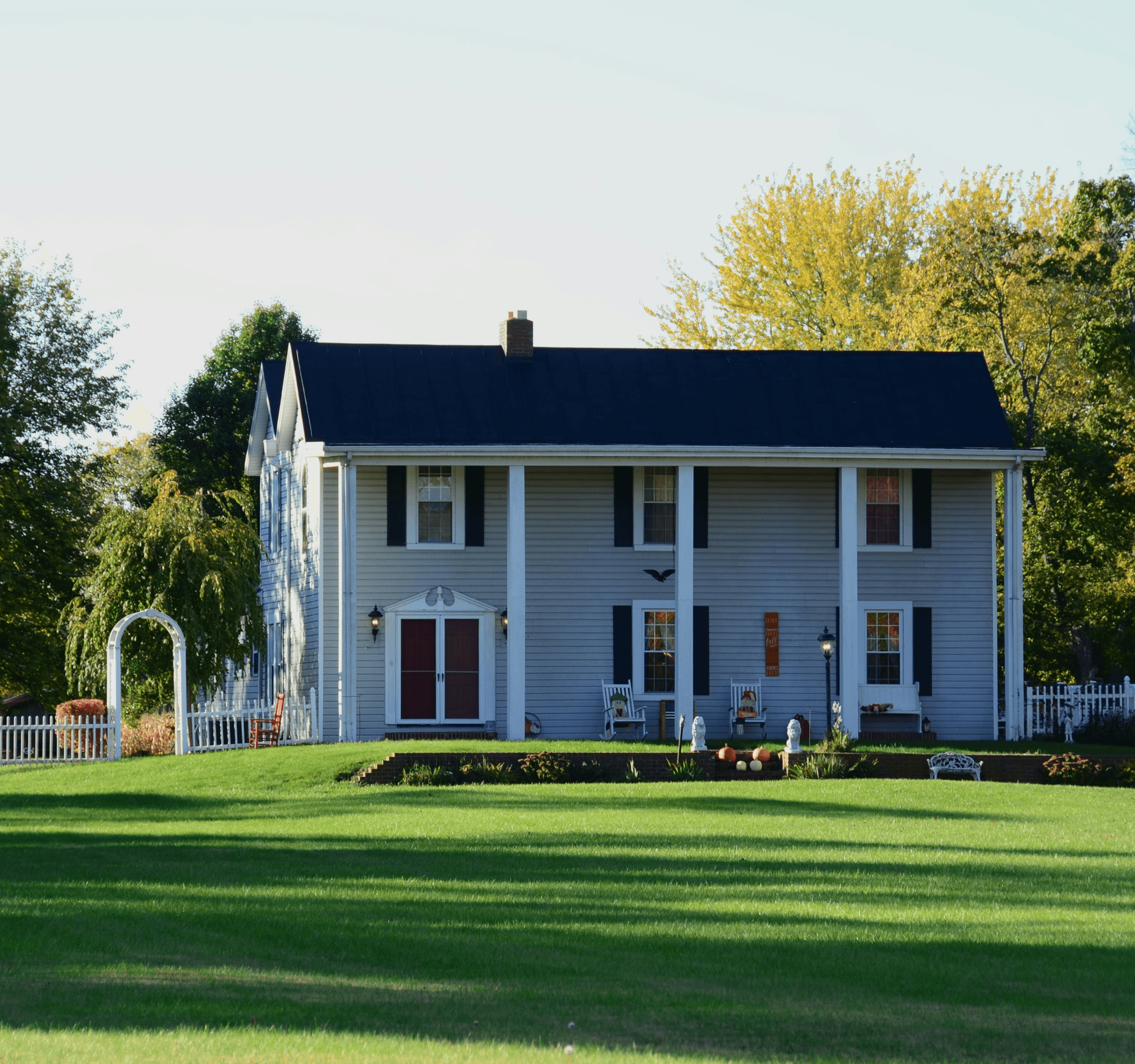Beautiful white farmhouse with black shutters and a well-maintained lawn.