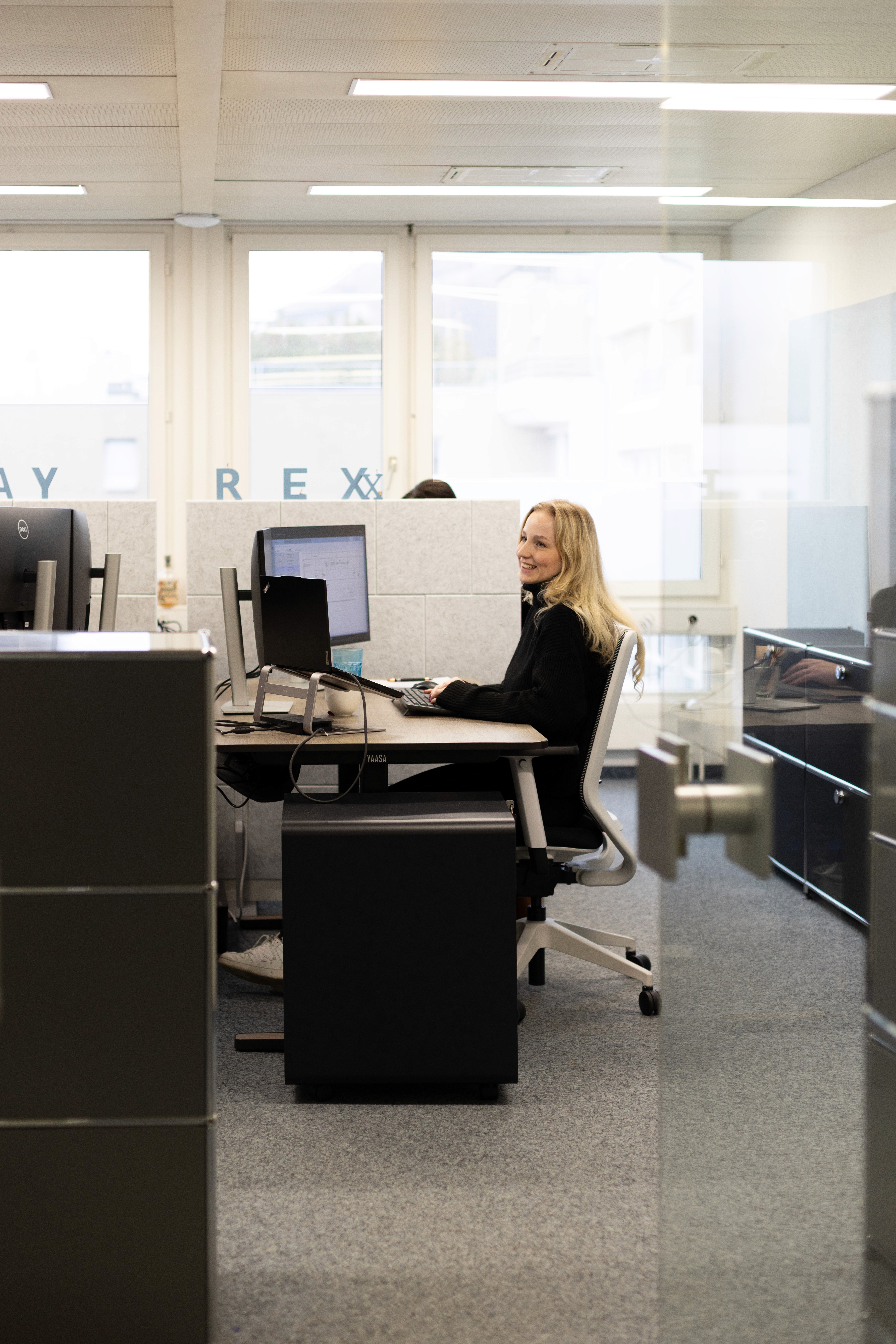 Young girl with headphones uses phone at desk