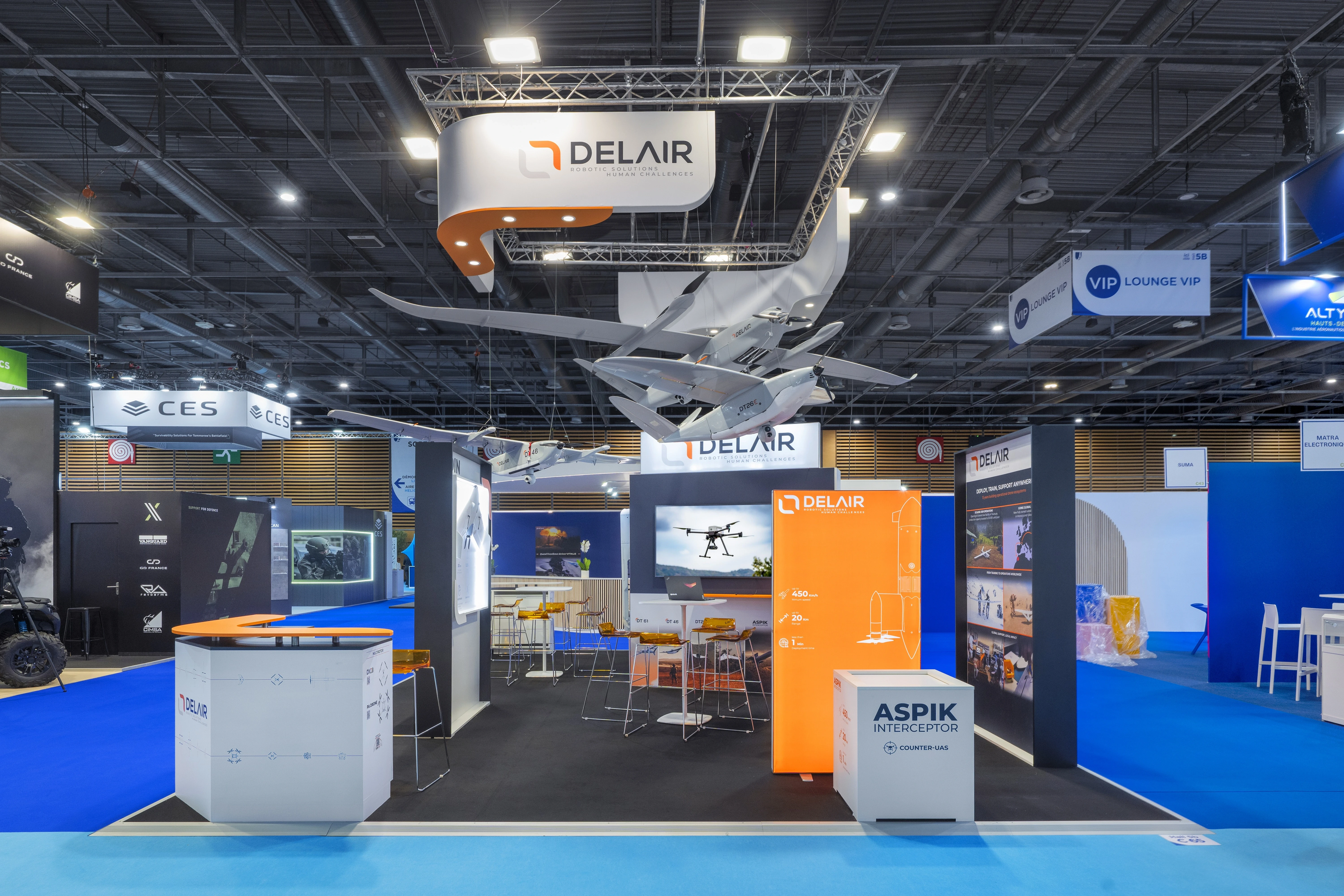 Stand Delair conçu et réalisé par Expace à Eurosatory 2026 – espace sur-mesure défense avec drones à voilure fixe suspendus, enseigne lumineuse, simulateur interactif et murs produits.